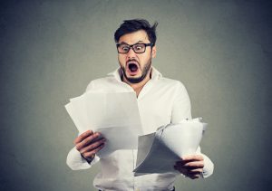 Shocked business man looking through papers with bills