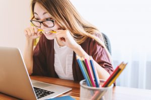 Woman biting pen stressing over technology